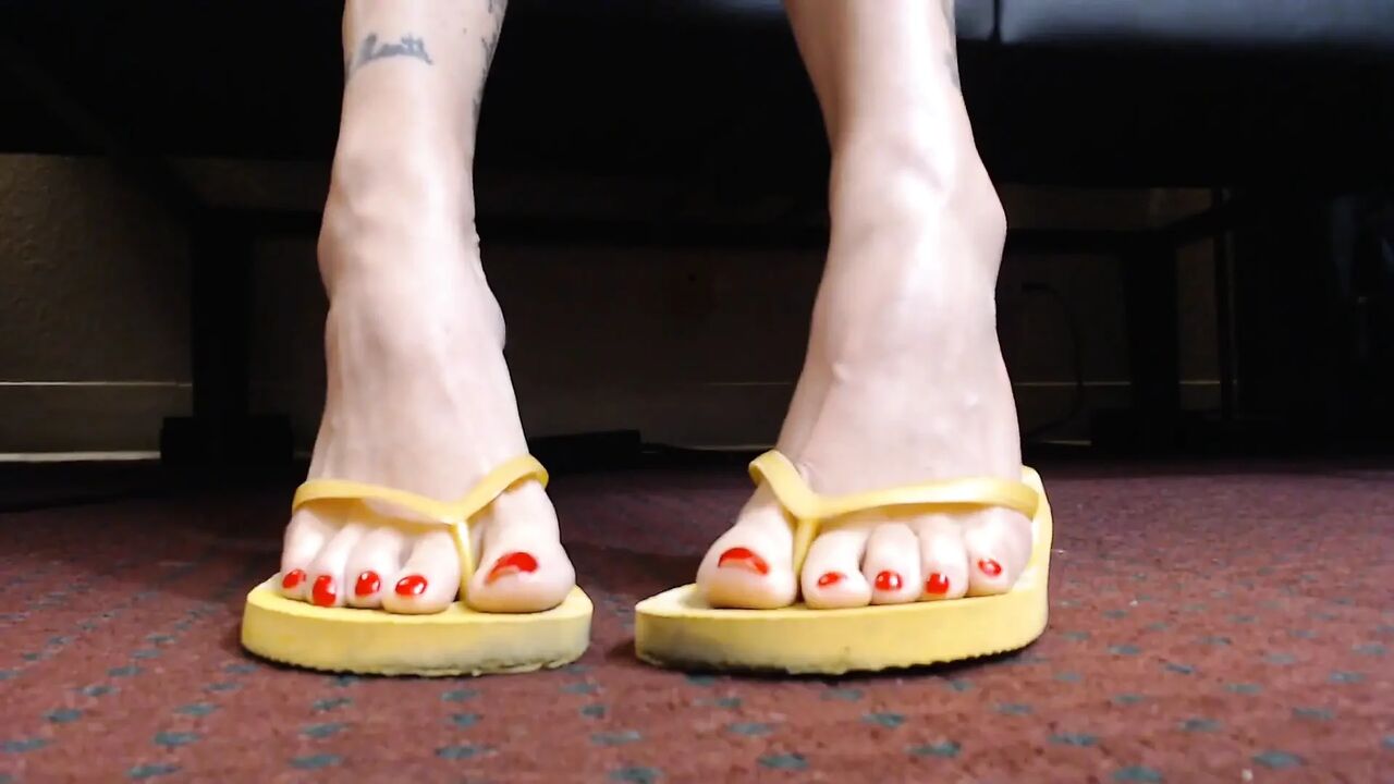 Red toenail wiggling yellow flipflops